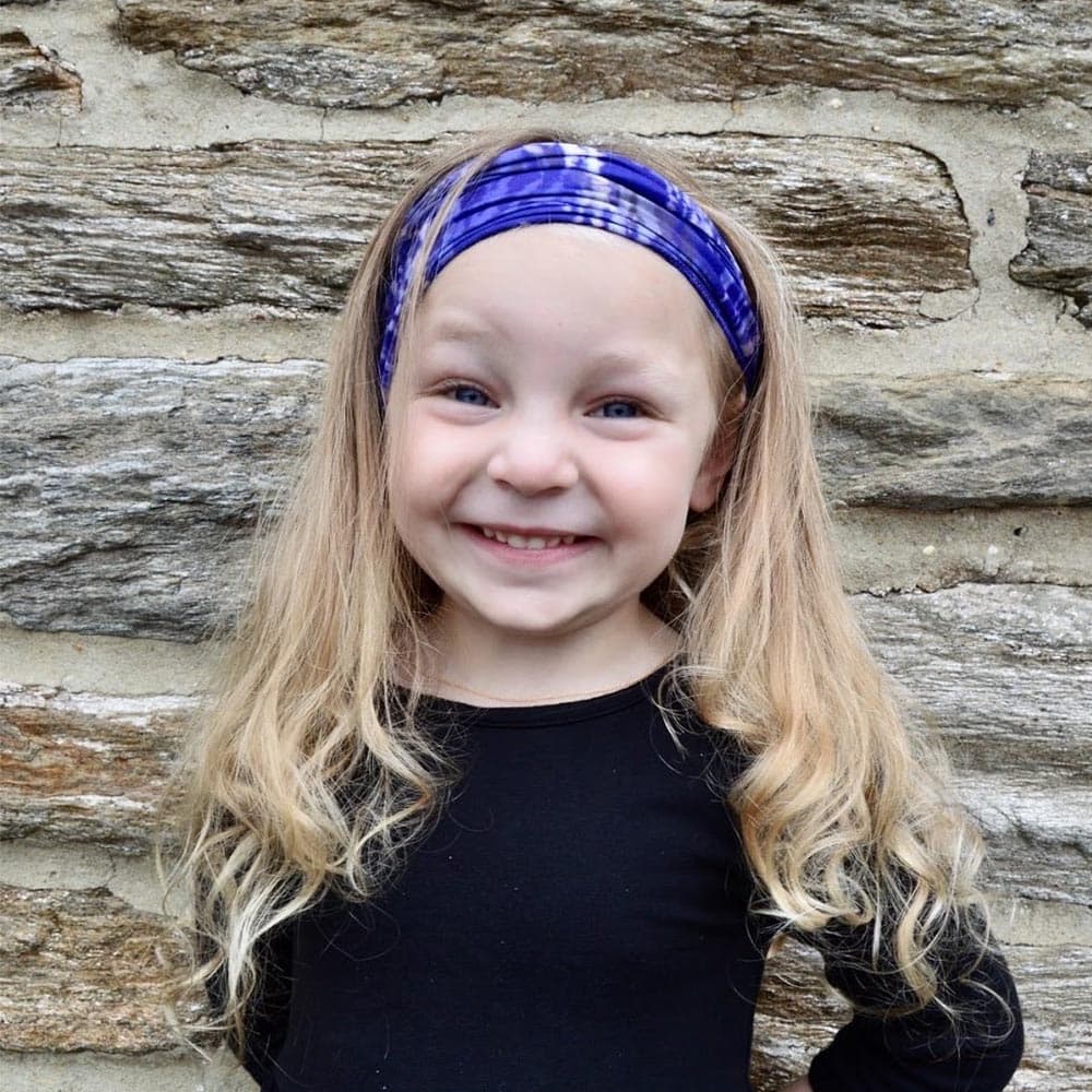 A kid female wearing a blue dreams face cover as a headband