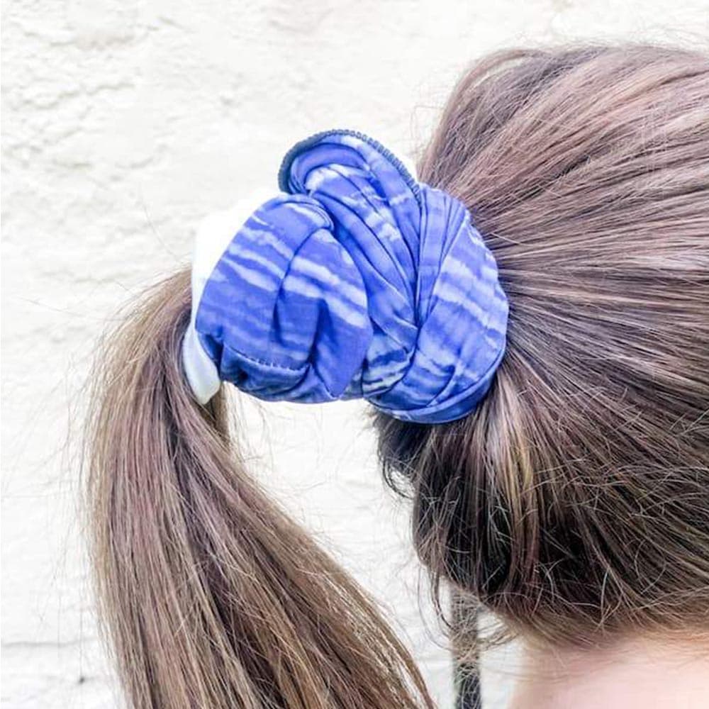 Adult woman using blue dreams face cover as a hair tie