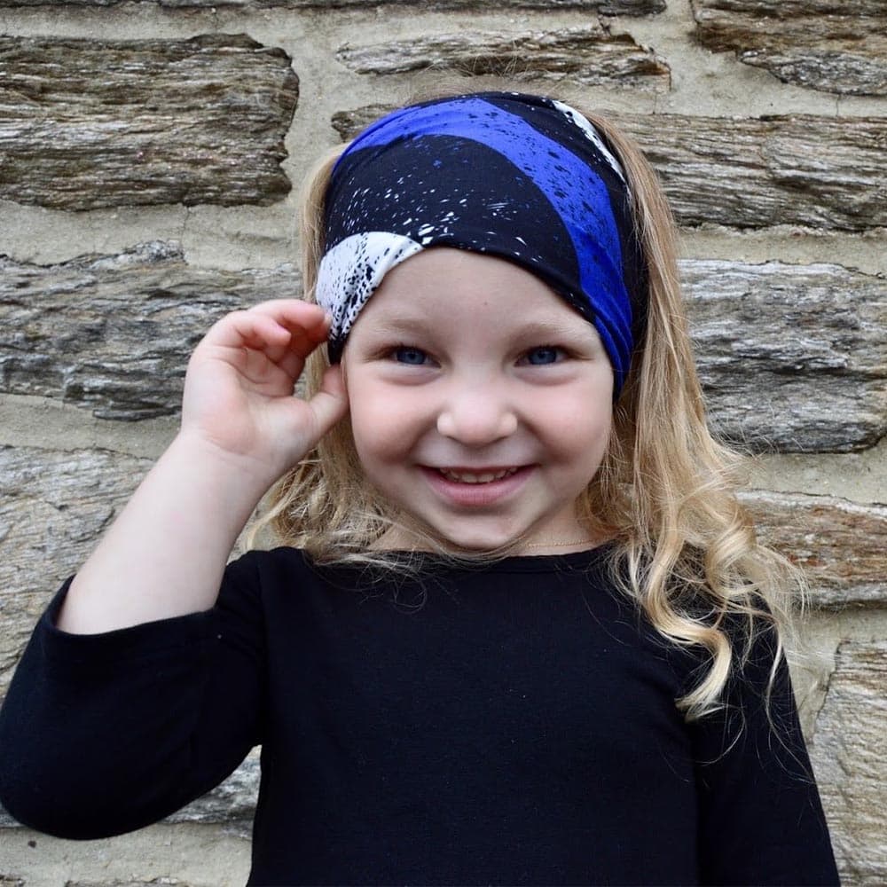 Little girl wearing a blue line pattern face cover as a headband by Jolina Boutique