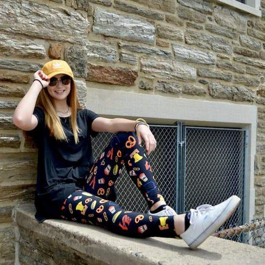 Model posing on ledge wearing philadelphia themed pattern leggings sold by Jolina Boutique
