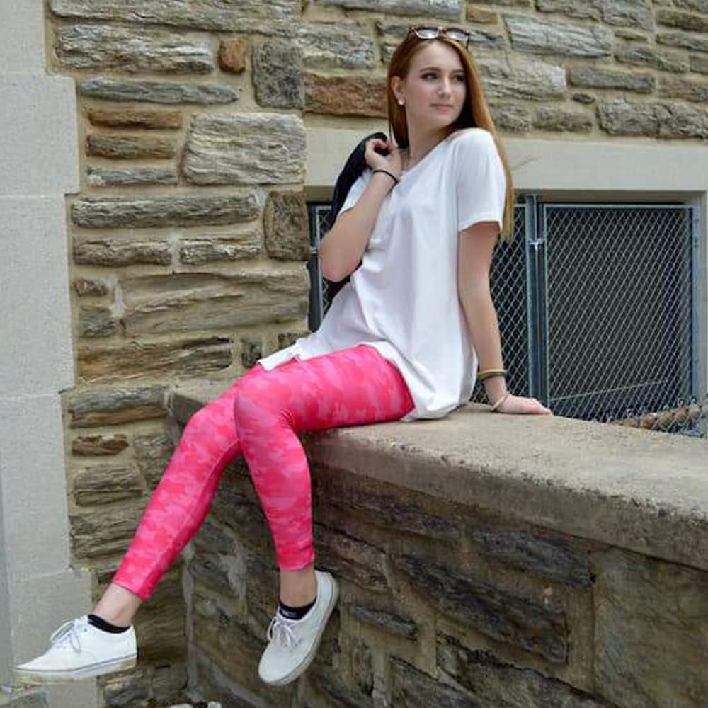 Model sitting on ledge wearing pink camo leggings